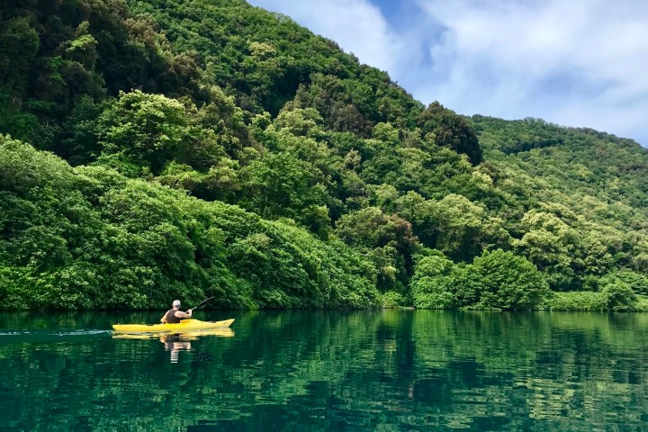 Man in yellow kayak by the hill